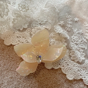 Detail of flower hair claw clip with cream iridescent finish and centered crystal