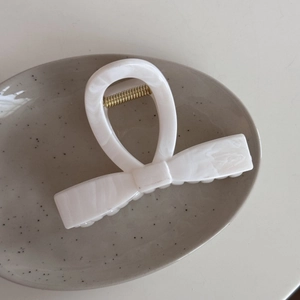 Detail view of marble pattern acetate hair claw clip with golden metal spring