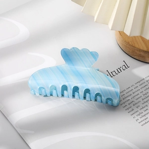 Detail of light blue and white striped acetate hair claw clip on wooden base