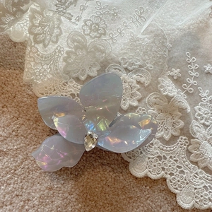 Detail of iridescent blue flower hair claw clip with water-drop rhinestone on lace
