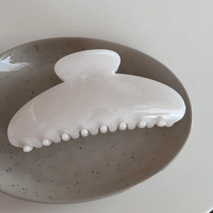 Close-up of a large cream marble texture hair claw clip on a stylish ceramic plate