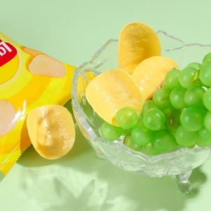 Macro detail of realistic artificial potato chips and green grapes in a glass bowl
