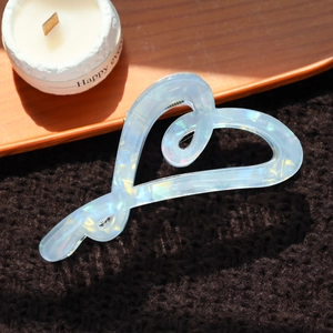 Détail d'une pince à cheveux cœur bleu clair irisé avec effet aurora sur tissu tricoté