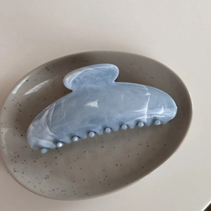 Detail of light blue marble textured hair claw clip on a ceramic tray display