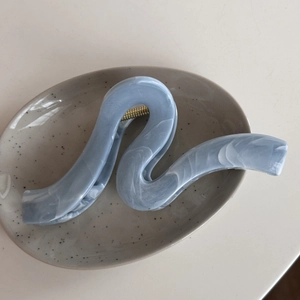Macro view of blue marble texture hair claw clip with golden metal spring detail