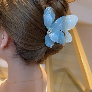 Blue iridescent butterfly hair claw clip with rhinestones worn by a model in a side view