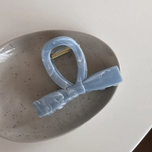 Close-up of a blue marble patterned acetate hair claw clip on a ceramic tray