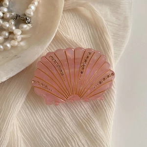 Détail d'une pince à cheveux coquillage rose avec strass et fini nacré brillant