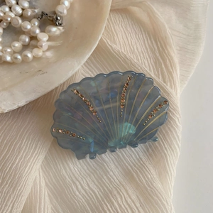 Détail macro d'une pince à cheveux en acétate en forme de coquillage avec strass brillants