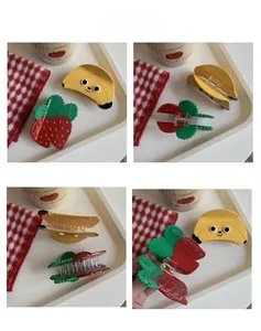 Detail view of strawberry and banana fruit hair claws showing design and metal spring