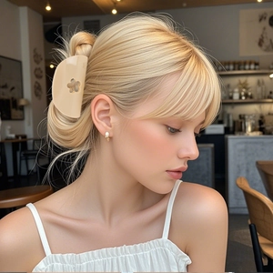 Pince à cheveux fleur jaune crème élégante pour femme sur un chignon de cheveux blonds