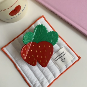 Detailed close-up of a cute strawberry-shaped hair claw clip with a glossy finish