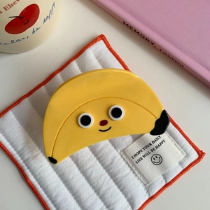 Close-up of a cute yellow banana hair claw clip with a cartoon face on a quilted fabric