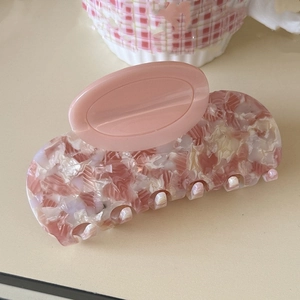 Close-up of pink acetate hair claw clip with marble texture and matte oval handle