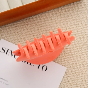 Détail d'une pince à cheveux orange pêche brillante sur un tissu beige doux