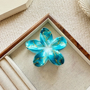 Detail of blue marble floral hair claw clip on wooden jewelry display tray