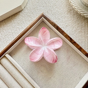 Detail of pink marble pattern plumeria hair claw clip on a linen display tray