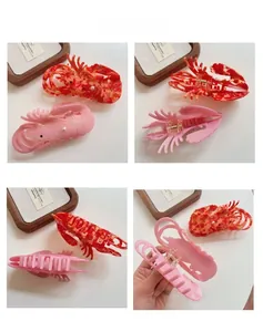 Detail view of lobster-shaped acetate hair claw clips with marble texture and pearl beads