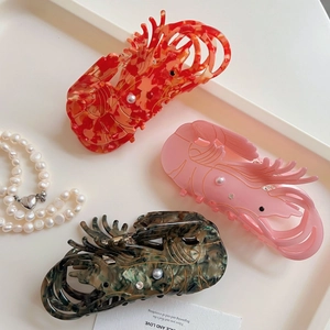 Elegant lobster-shaped acetate hair claws with pearls and rhinestones on a tray
