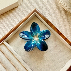 Detail showing blue marble textured flower hair claw clip with golden veins on display