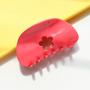 Détail macro de la pince à cheveux fleur rose brillante avec découpe et gravure de marque