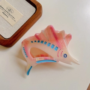 Detailed close-up of a swordfish-shaped acetate hair claw in pink and blue colors