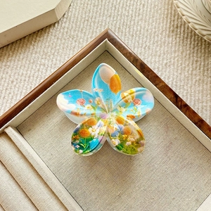 Detailed macro view of a floral hair claw clip featuring artistic nature scene illustrations