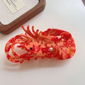 Detailed close-up of a red lobster hair claw clip with elegant marble acetate texture
