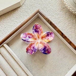 Detail of flower hair claw clip with purple marble texture on wooden display tray
