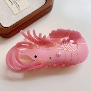 Detailed view of pink acetate lobster hair claw clip with pearls and gold accents