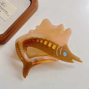 Close-up of marble amber acetate hair claw clip in fish shape with golden details