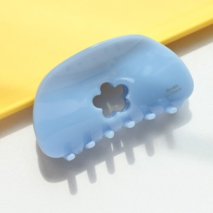Gros plan sur une pince à cheveux fleurie bleu clair avec lettrage Barrette La France