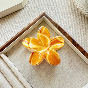 Detail view of tropical plumeria claw clip with marble texture on linen display