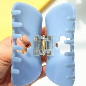 Détail d'une pince à cheveux papillon bleu clair avec un ressort métallique doré