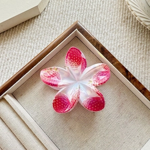 Exquisite plumeria hair claw with strawberry prints in a warm wooden tray setting