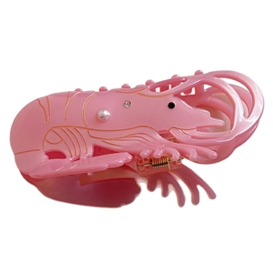 Pink lobster-shaped acetate hair claw clip with pearl and rhinestone accents on white background