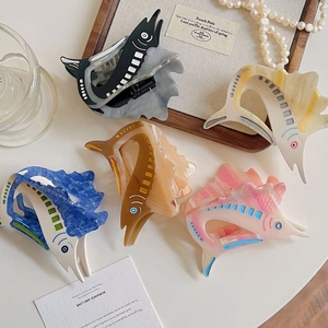 Elegant fish-shaped acetate hair claws in five colors on a white luxury aesthetic display