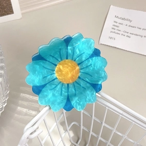 Macro detail of blue acetate flower hair claw clip with marble texture on white wire basket