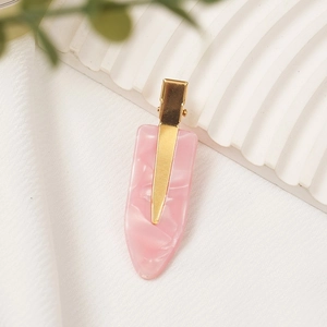 Pink marble texture acetate hair clip with golden metal base on minimalist background