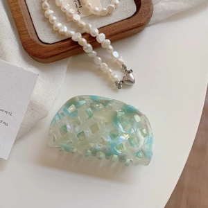 Detail eines blauen Haarklammer-Clips mit Waffelmuster und einer Perlenkette mit Herz