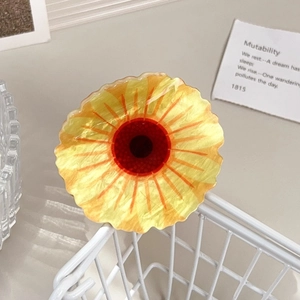 Detail of sunflower hair claw clip made of yellow acetate resin on a white basket