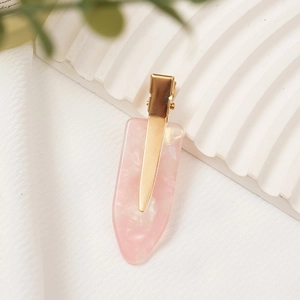 Pink marble acetate hair clip with golden metal base on a white textured board