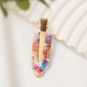 Detail shot of colorful acetate hair clip with floral pattern and gold metal base