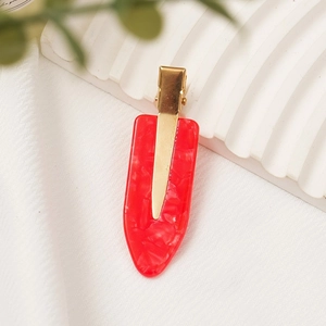Close-up of a red acetate hair clip with marble texture on white fabric and stone