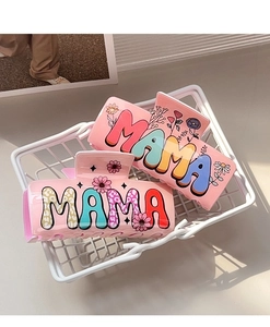 Detailed close-up of pink acrylic hair claw clips with MAMA lettering and daisy patterns