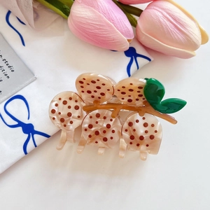 Detailansicht der Haarspange im Keks-Design mit grünen Blättern auf floralem Stoff
