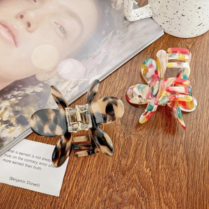 Pinces à cheveux papillon en écaille et motif mosaïque sur une surface en bois