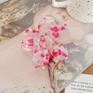 Détail de la pince à cheveux en acétate rose avec motif floral et pétales translucides