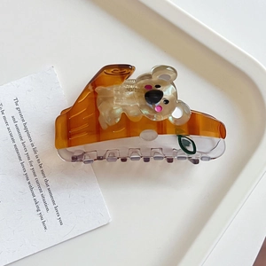 Detail view of a cute koala hair claw clip with transparent amber acetate and spring