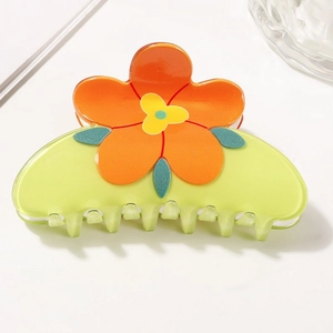 Détail d'une pince à cheveux vert clair translucide avec une fleur orange vif décorative